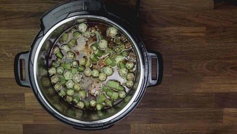 Instant Pot Gumbo Recipe (Pressure Cooker Gumbo): layer fresh chopped okra on top of chicken thighs and andouille sausage in Instant Pot Pressure Cooker
